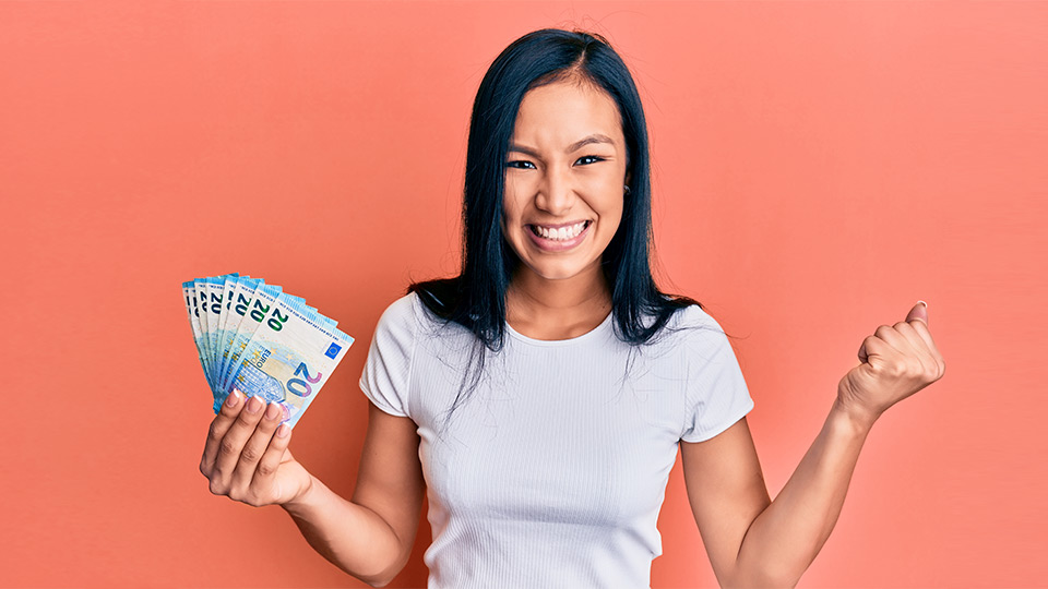 Eine Frau jubelt mit Geld in der Hand.